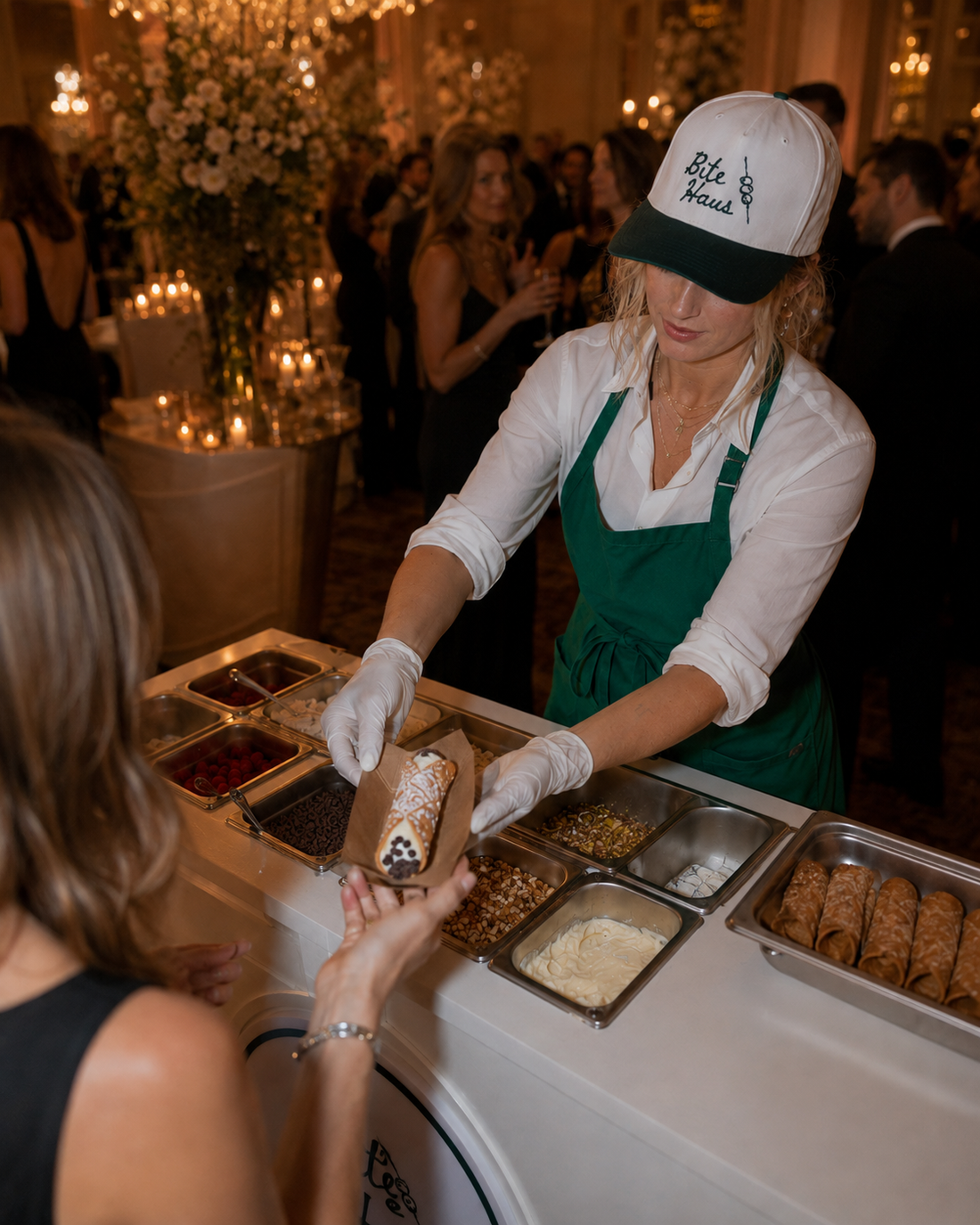 BiteHaus Live Cannoli Bar handing a fresh cannoli to a guest at a ballroom wedding