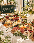 BiteHaus grazing table styled with florals, candles and charcuterie cones, with the BiteHaus cart behind